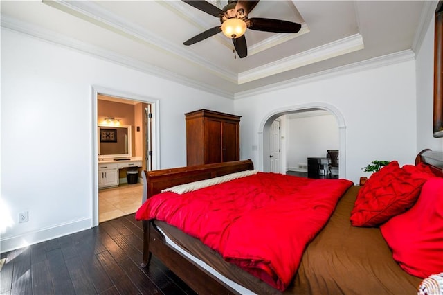 bedroom featuring ornamental molding, hardwood / wood-style floors, arched walkways, a raised ceiling, and a ceiling fan