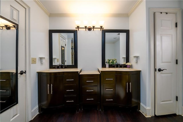 bathroom featuring a sink, wood finished floors, two vanities, and ornamental molding