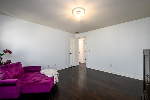 living area with baseboards, visible vents, and hardwood / wood-style flooring