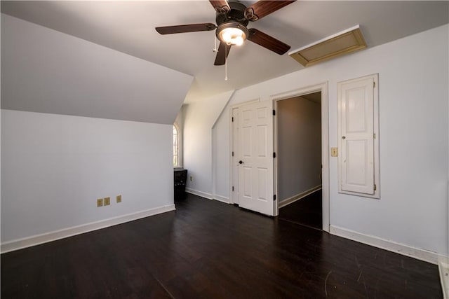 bonus room with a ceiling fan, baseboards, dark wood finished floors, attic access, and vaulted ceiling