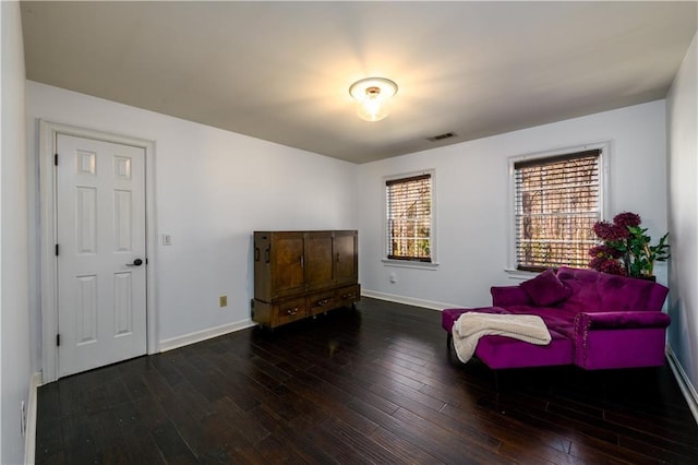 living area with baseboards, visible vents, and hardwood / wood-style flooring