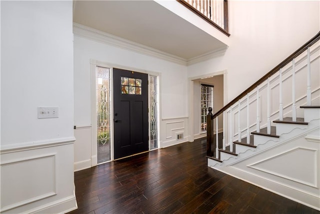 foyer with a decorative wall, crown molding, and wood finished floors