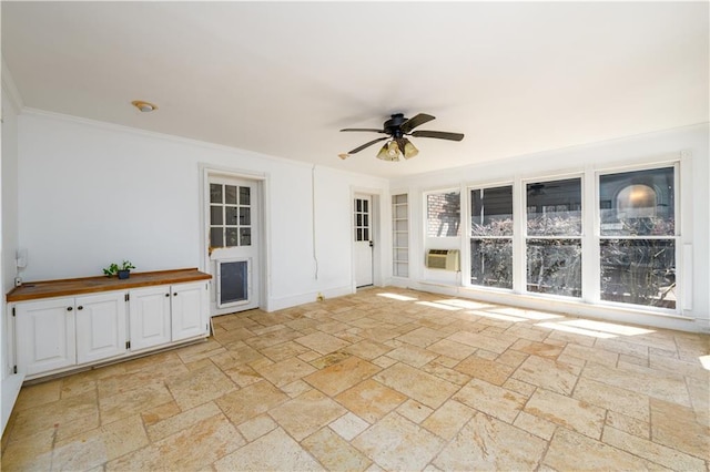 empty room featuring ornamental molding, stone tile floors, built in shelves, and ceiling fan