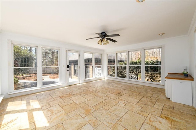 unfurnished sunroom with stone tile floors, crown molding, and a wealth of natural light