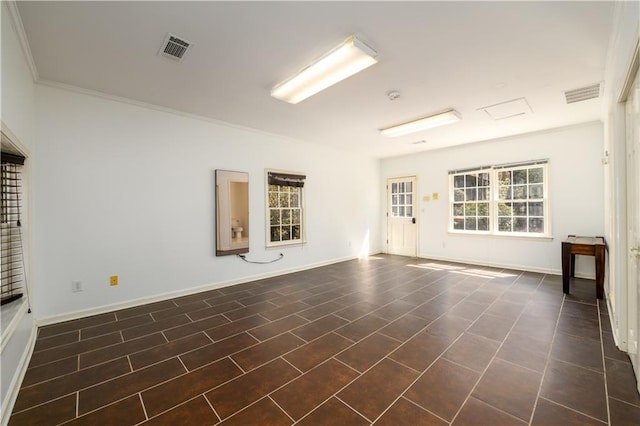 empty room with visible vents, crown molding, and baseboards