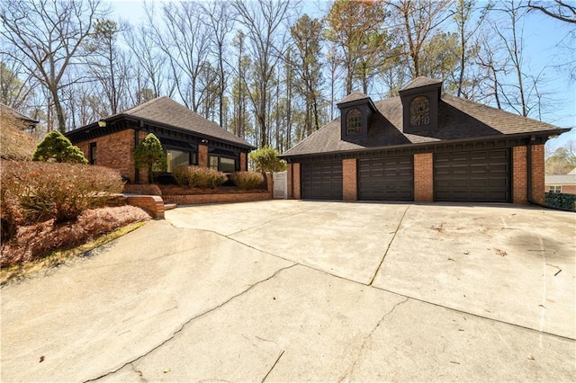 view of side of property featuring a detached garage, brick siding, and roof with shingles