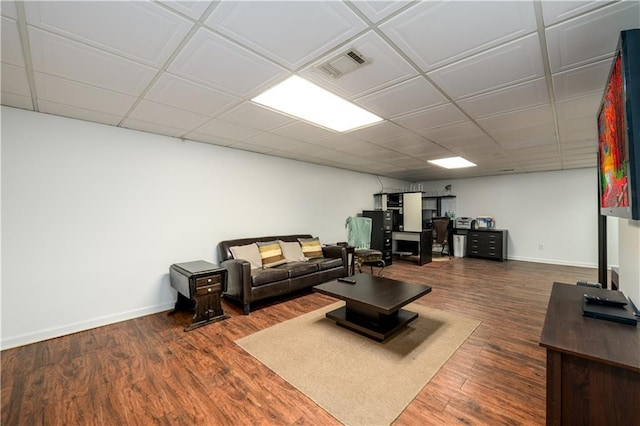 living room featuring visible vents, a drop ceiling, baseboards, and wood finished floors