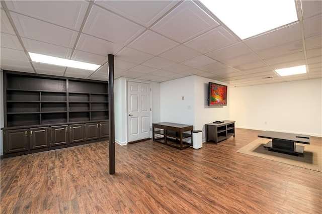 finished basement featuring built in features, a drop ceiling, baseboards, and wood finished floors