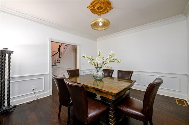 dining space featuring visible vents, ornamental molding, stairs, dark wood-type flooring, and a decorative wall