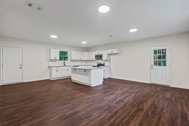 2091 Chestnut Log Dr, Lithia Springs, GA 30122 - kitchen featuring appliances with stainless steel finishes, dark wood finished floors, a center island, white cabinets, and light countertops