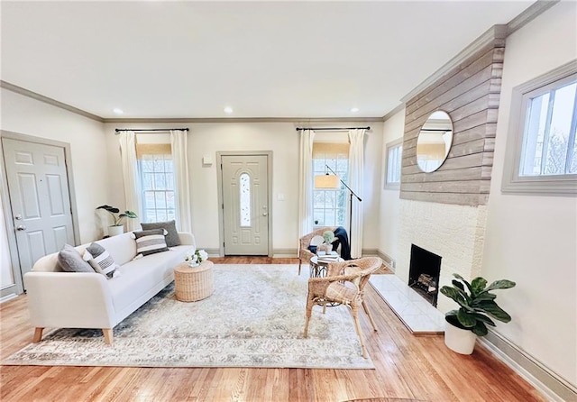 living room featuring ornamental molding, a fireplace, baseboards, and wood finished floors