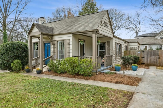 view of front of property with a front lawn, fence, covered porch, and a chimney