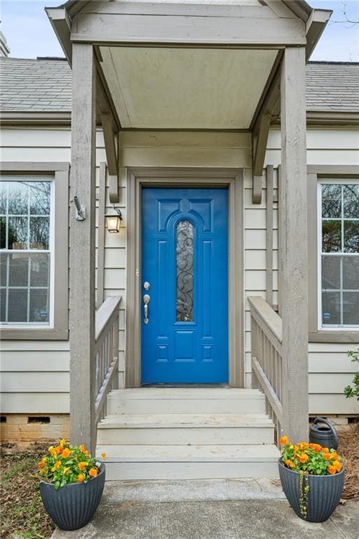 property entrance featuring a shingled roof and crawl space