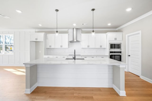 kitchen featuring white cabinetry, wall chimney range hood, stainless steel appliances, hanging light fixtures, and a large island