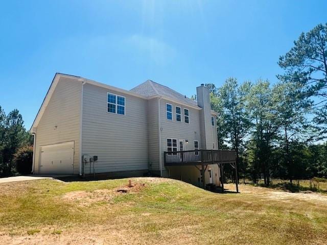 back of house featuring a deck, a garage, and a yard