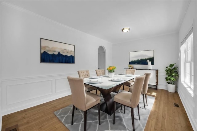 dining area featuring hardwood / wood-style floors, ornamental molding, and a healthy amount of sunlight