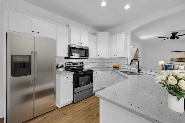 kitchen with light wood-type flooring, white cabinets, ceiling fan, appliances with stainless steel finishes, and sink