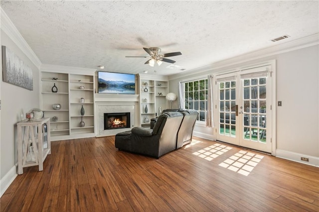 living area with a textured ceiling, hardwood / wood-style floors, crown molding, a ceiling fan, and french doors