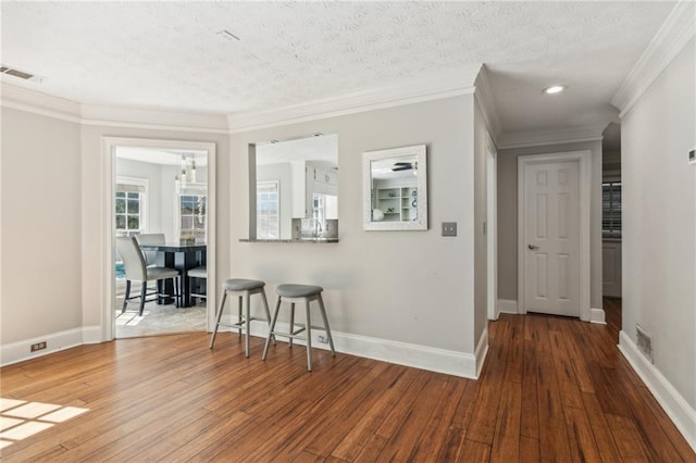 hallway featuring hardwood / wood-style flooring, crown molding, baseboards, recessed lighting, and a textured ceiling