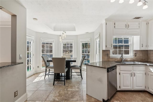 kitchen with stainless steel dishwasher, dark stone countertops, tasteful backsplash, white cabinetry, and a textured ceiling