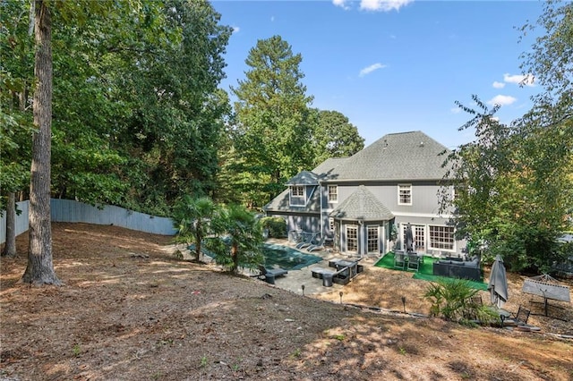 rear view of house with a patio, a swimming pool, and fence