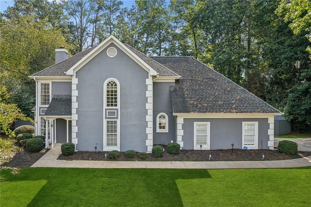 view of front of property with stucco siding, a chimney, and a front yard