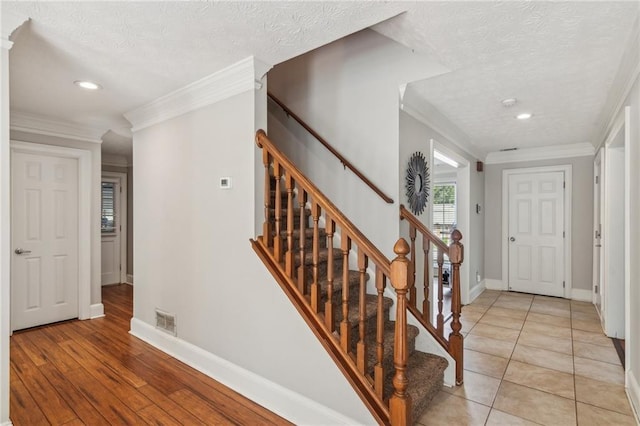stairs featuring a textured ceiling, baseboards, crown molding, recessed lighting, and wood finished floors