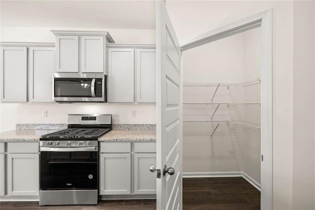 kitchen featuring white cabinets, dark hardwood / wood-style flooring, stainless steel appliances, and light stone counters