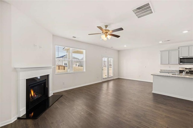 unfurnished living room with ceiling fan, dark hardwood / wood-style flooring, and sink