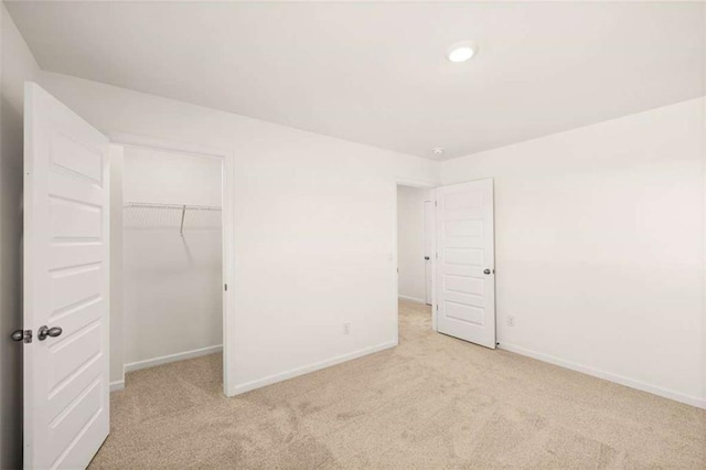 unfurnished bedroom featuring light colored carpet, a spacious closet, and a closet