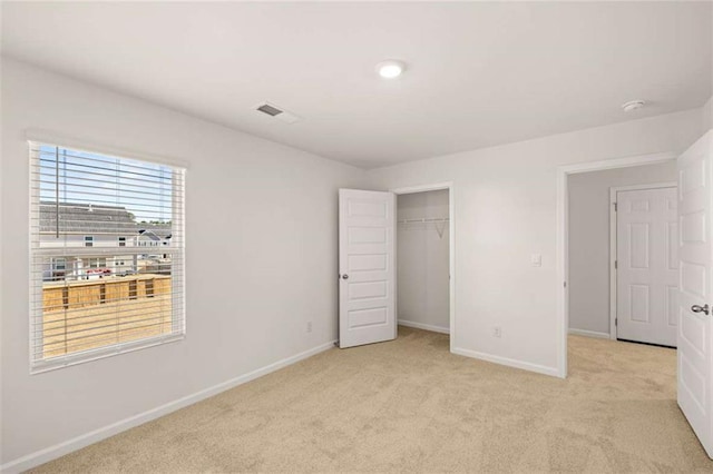 unfurnished bedroom featuring light carpet and a closet