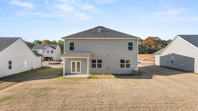 rear view of house with french doors, a patio, central AC, and a lawn