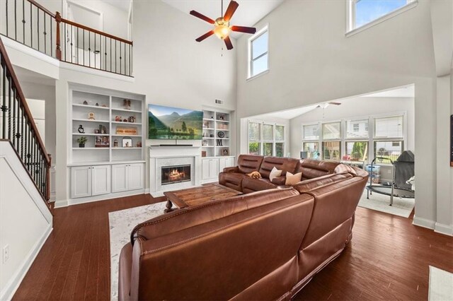 337 Spotted Ridge Cir, Woodstock, GA 30188 - living area featuring a ceiling fan, a towering ceiling, a warm lit fireplace, stairway, and dark wood-style floors