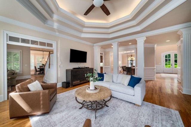 living area with ornate columns, crown molding, ceiling fan, a chandelier, and wood finished floors