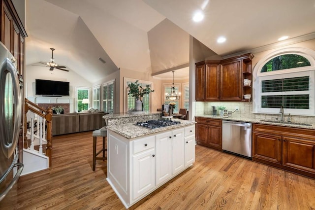 kitchen with appliances with stainless steel finishes, a sink, ceiling fan, open floor plan, and light wood-style flooring