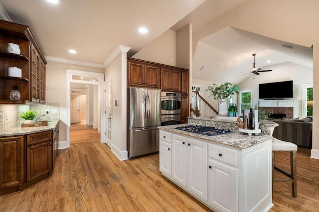 kitchen featuring stainless steel appliances, a ceiling fan, a fireplace, decorative backsplash, and open shelves