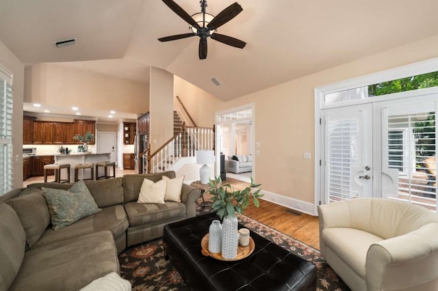 living room featuring stairs, wood finished floors, ceiling fan, vaulted ceiling, and baseboards