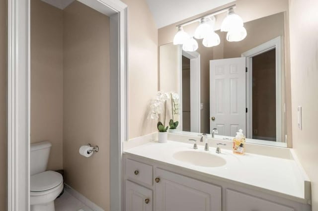 bathroom with toilet, vanity, tile patterned flooring, and baseboards