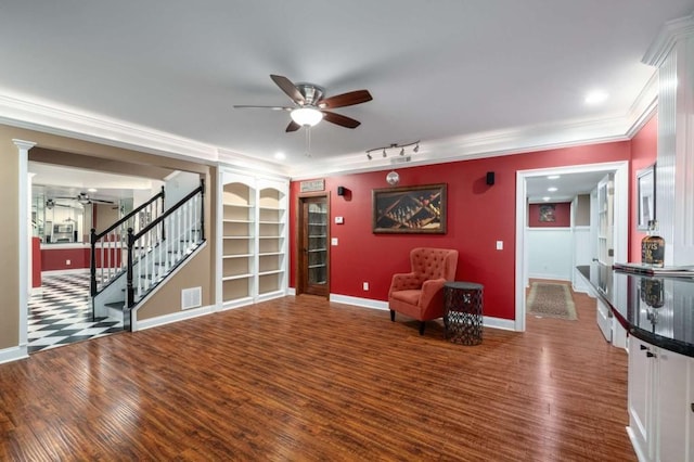 living area with ceiling fan, stairs, wood finished floors, baseboards, and ornamental molding