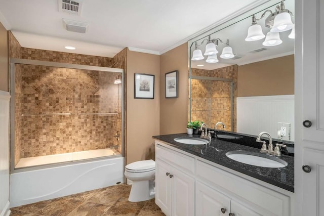 bathroom featuring ornamental molding, toilet, combined bath / shower with glass door, double vanity, and wainscoting