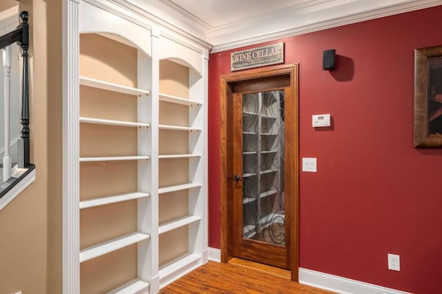 hallway with ornamental molding, wood finished floors, and baseboards