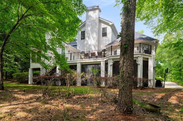 rear view of property featuring a balcony and a chimney