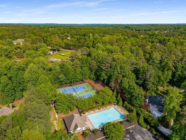 drone / aerial view of a heavily wooded area and a pool area