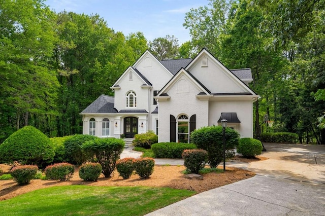 french provincial home with roof with shingles and stucco siding