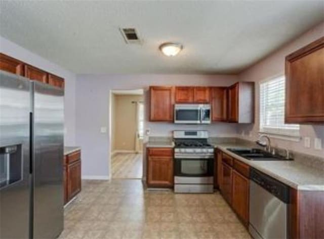 6684 Crane Ave, Fairburn, GA 30213 - kitchen featuring appliances with stainless steel finishes, a sink, light countertops, brown cabinets, and baseboards