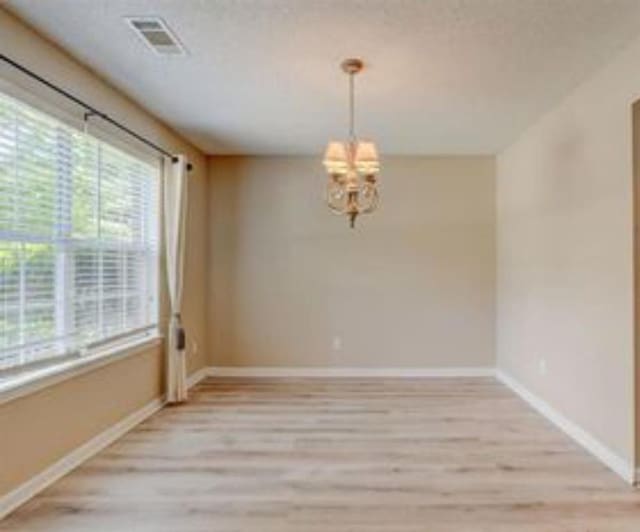 6684 Crane Ave, Fairburn, GA 30213 - unfurnished dining area with a chandelier, light wood finished floors, and baseboards