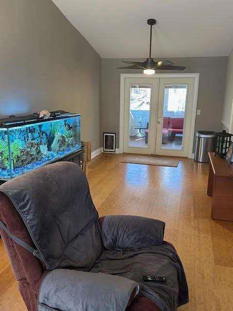 living area featuring lofted ceiling, baseboards, and a ceiling fan