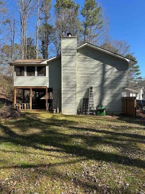 view of property exterior featuring a sunroom, a lawn, and a chimney