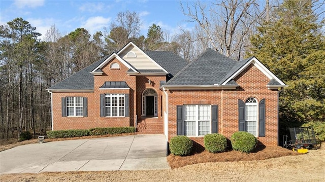 traditional home with roof with shingles and brick siding