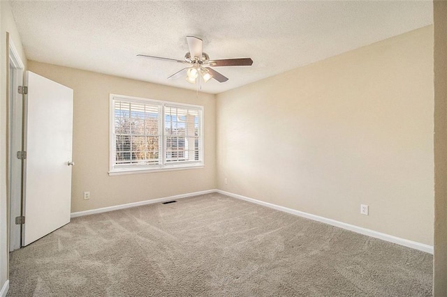 carpeted spare room featuring ceiling fan and a textured ceiling